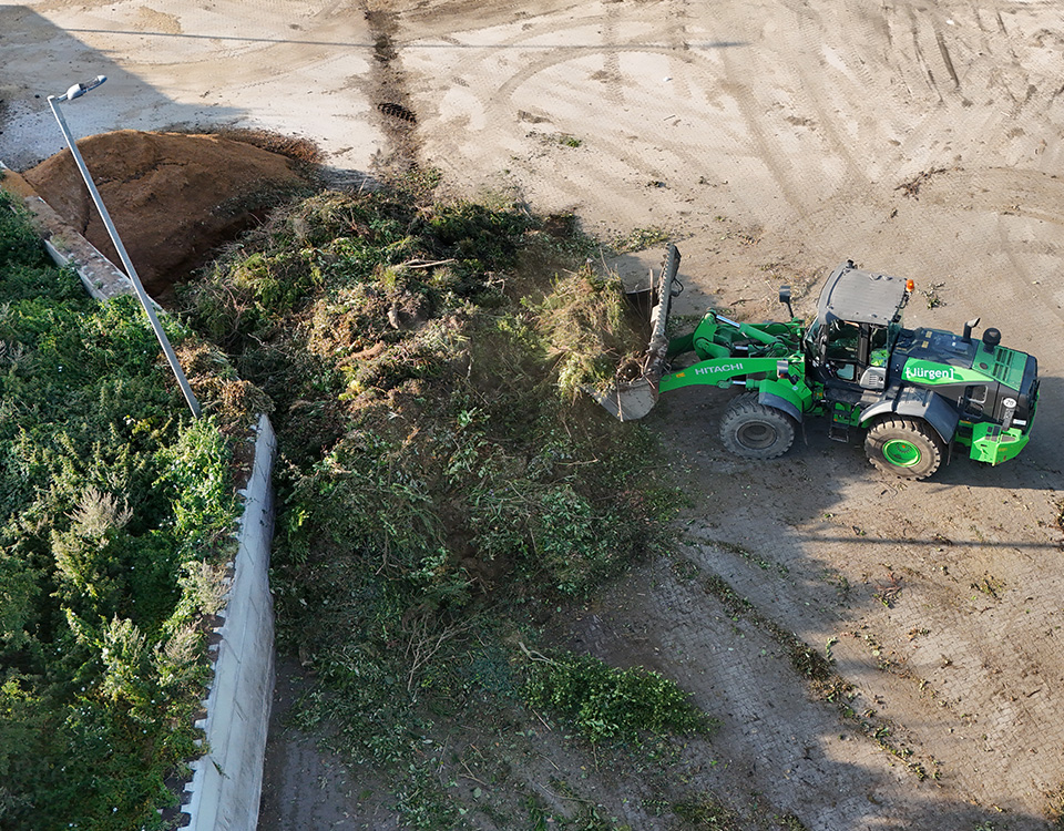 Grüner Bagger kompostiert Grünabfälle