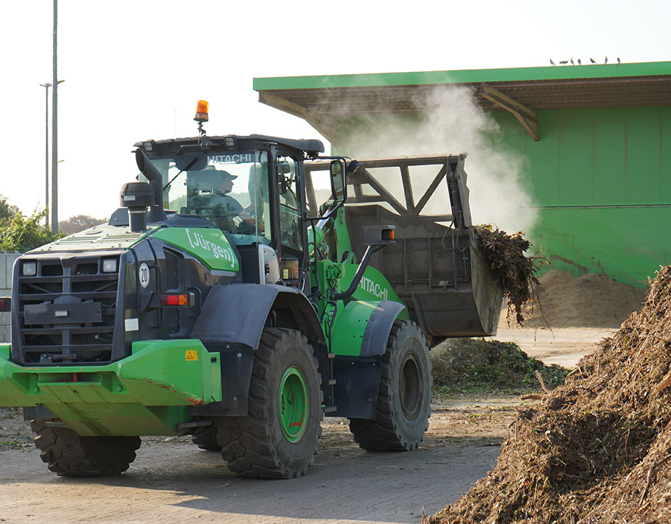 Grüner Bagger transportiert Kompost